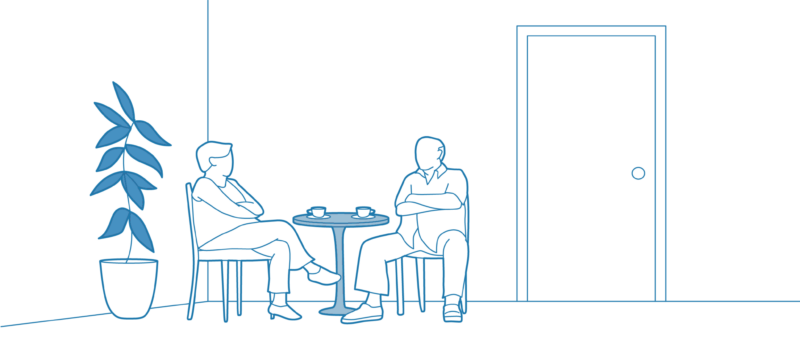 Two older adults sitting and chatting in a common room