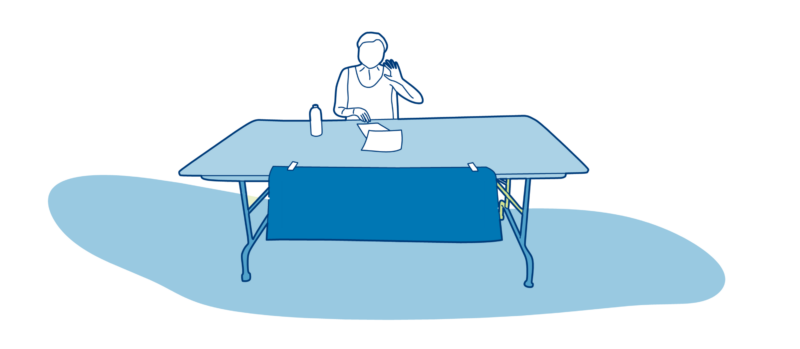 woman sitting behind a table and waving hello